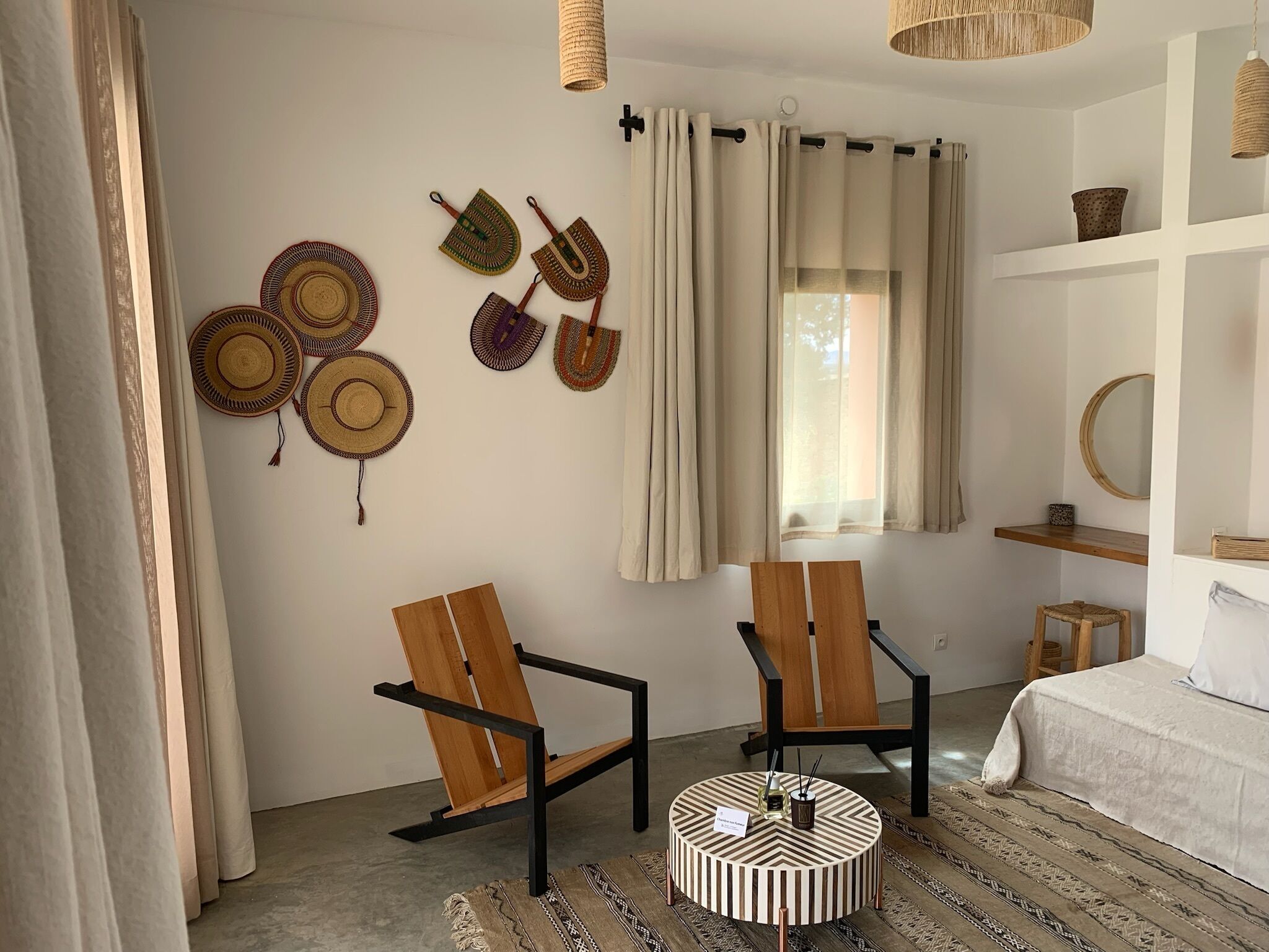 A room with two wooden chairs, a round table, and a window with curtains.