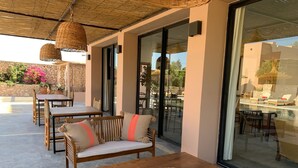An outdoor seating area with wooden furniture and a woven table runner. - Dar Almajula (Essaouira)