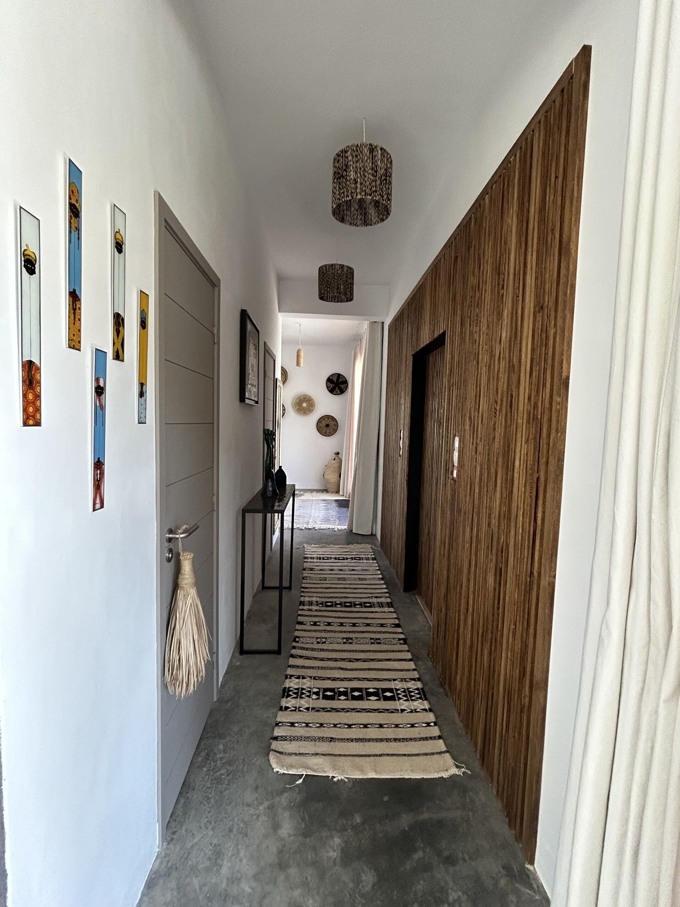 Un couloir avec un tapis à motifs, un mur en bois et un luminaire au plafond.