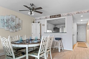Un coin repas avec une table ronde, des chaises blanches et un ventilateur de plafond.