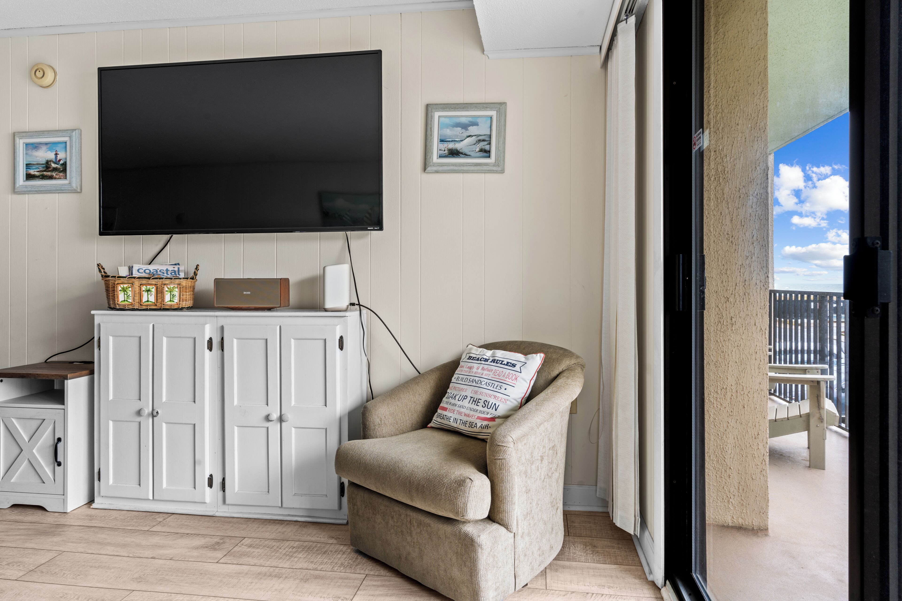 Une pièce dotée d’un téléviseur à écran plat, d’un fauteuil confortable, d’une armoire blanche et offrant une vue sur l’extérieur.