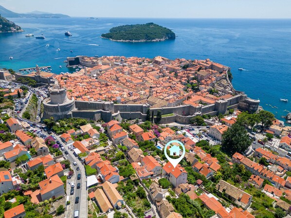 An aerial view of a historic city with a prominent fortification, a marina, and a small island.