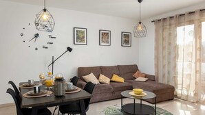 A modern living room with a brown sofa, dining table with chairs, and artwork on the wall. - Apartment Why Not (Dubrovnik)