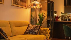 Un salón con un sofá amarillo, cojines de estampado de leopardo, una mesa de centro redonda y una alfombra estampada.