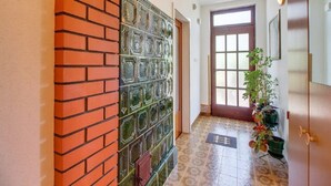 A hallway with a tiled floor, a brick wall, a glass door, and a wooden door. - Apartment Blamax (Mali Losinj)