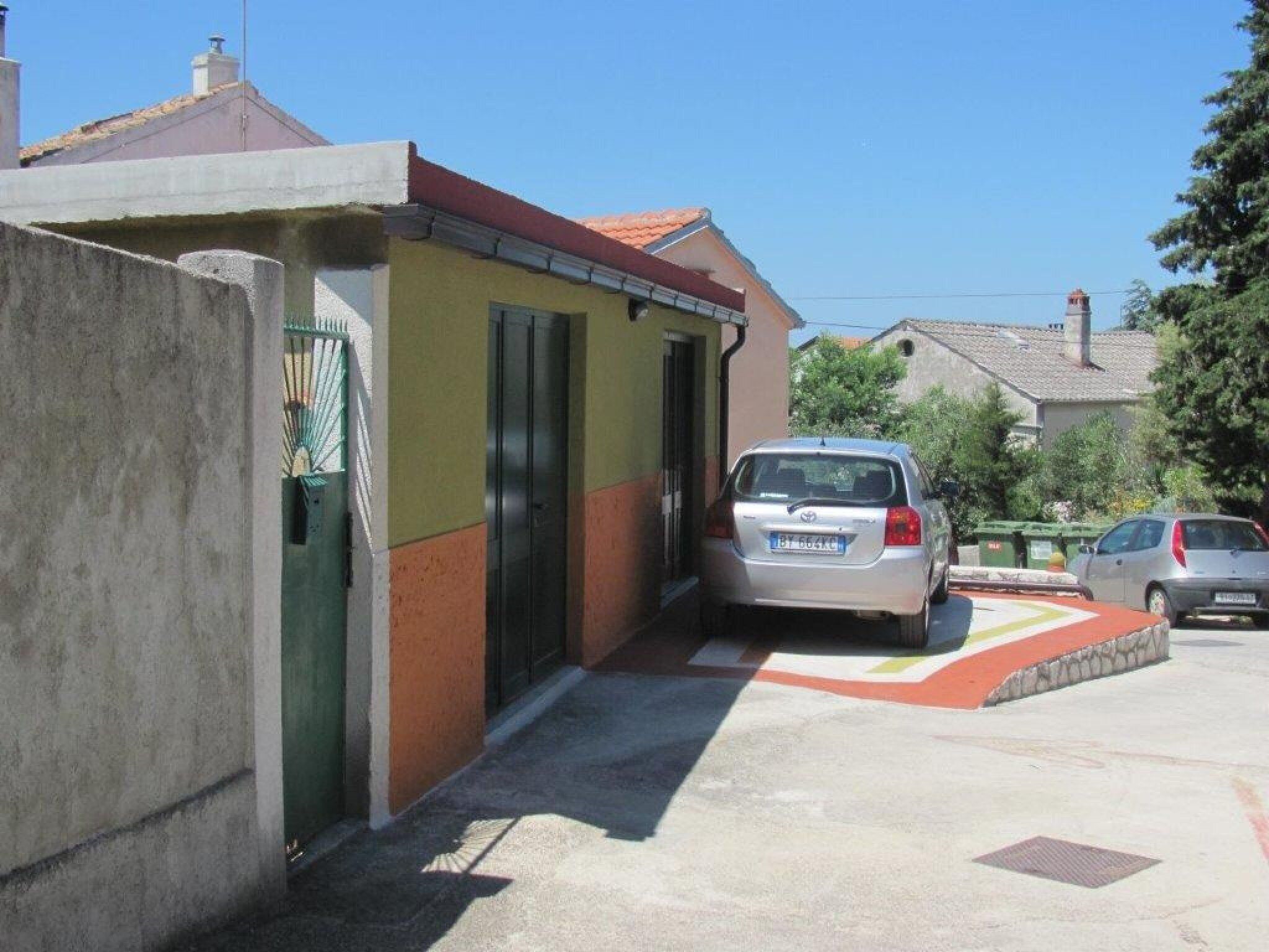 A residential area with a parked car in front of a house with a red roof and a yellow wall.