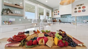 A kitchen with a charcuterie board, wine glasses, and a large window.