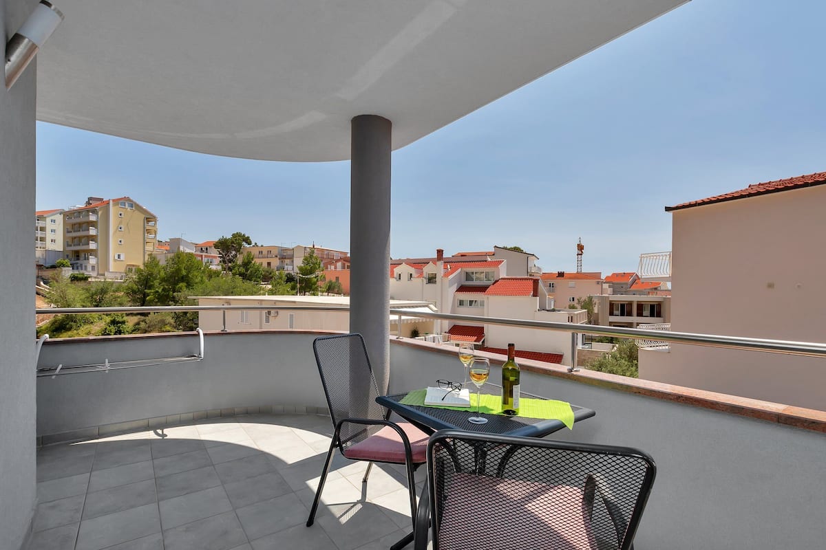 Een balkon met een tafel, stoelen en een fles wijn.