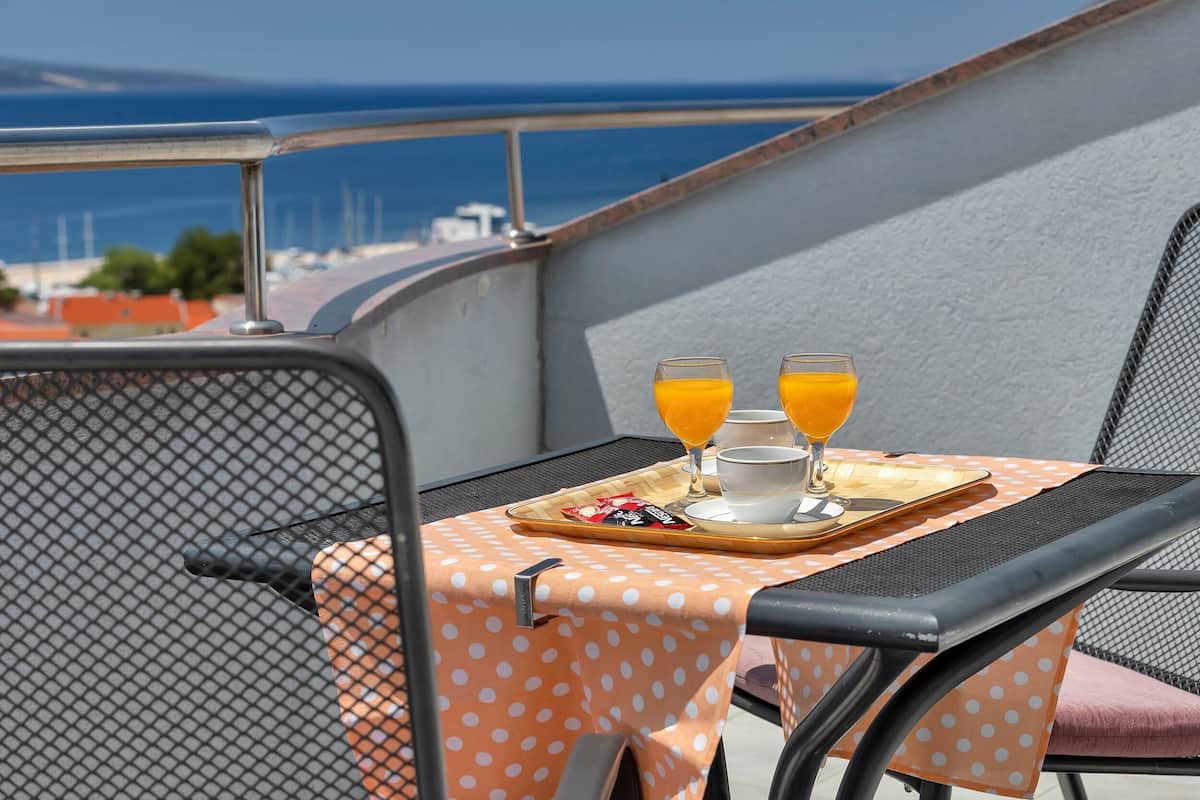 Een balkon met een tafel gedekt voor het ontbijt, inclusief sinaasappelsap en een dienblad met etenswaren.