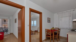 A dining area with a wooden table and chairs, a kitchen counter, and a view of the balcony.