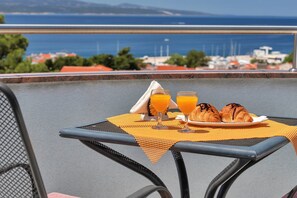 Una mesa con cruasanes y jugo de naranja, con vistas al mar.