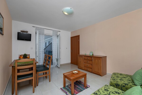 Una sala de estar con televisión, muebles de madera, una mesita y un sofá.