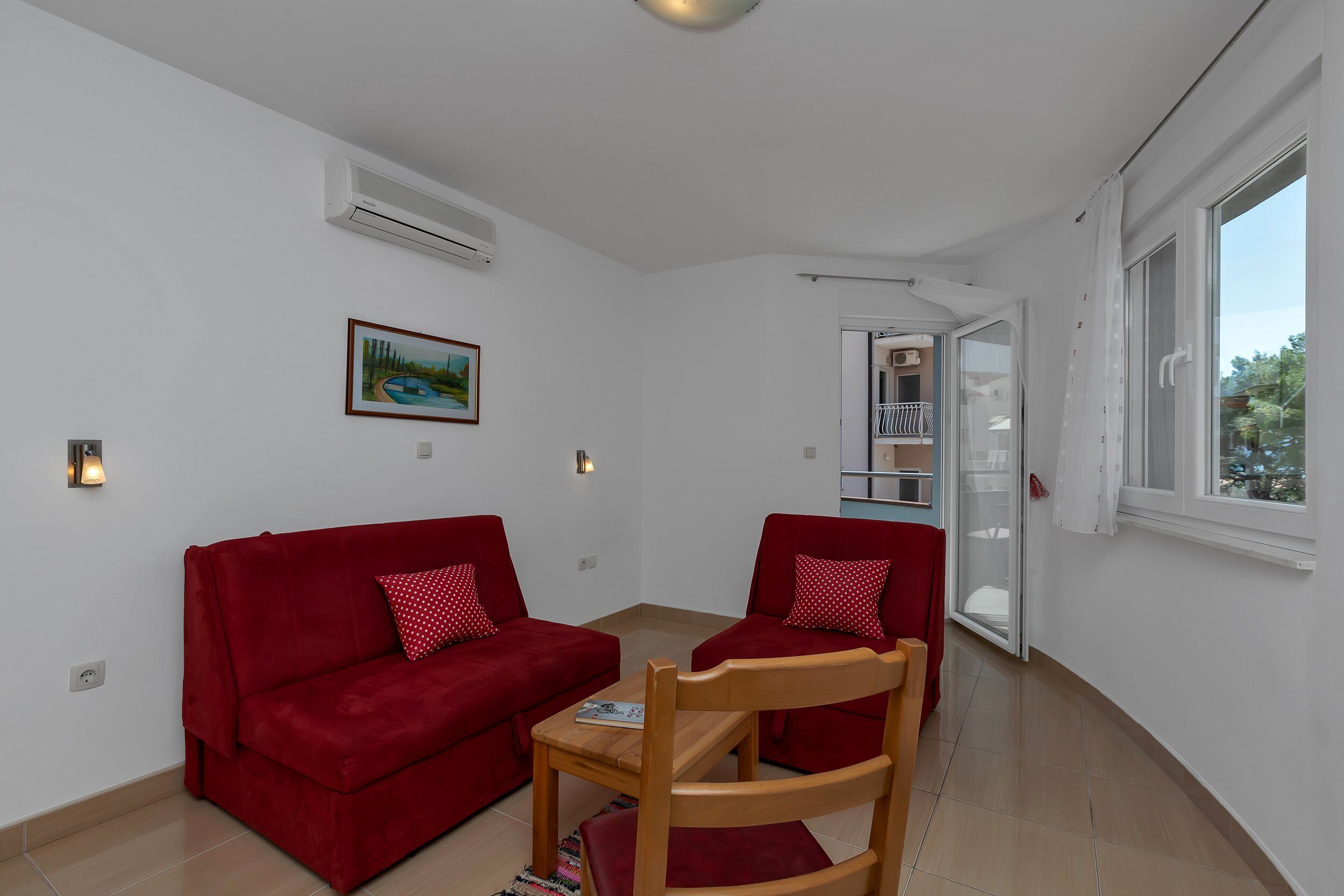 Et værelse med to røde sofaer, en træstol, et lille bord og et vindue med udsigt.