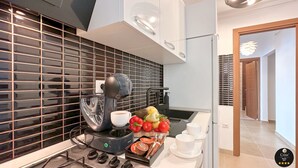 A modern kitchen with a coffee machine, fresh produce, and a view of the hallway.