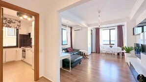 A modern apartment with a kitchen, living area, dining space, and a large window with curtains.