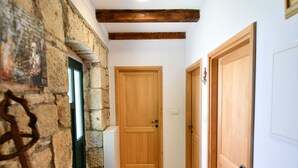 A hallway with a stone wall, wooden door, and a wooden bench. - Apartment Rural Podastrana (Hrvace)