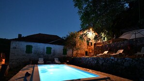 A swimming pool with lounge chairs and a stone wall. - Apartment Rural Podastrana (Hrvace)