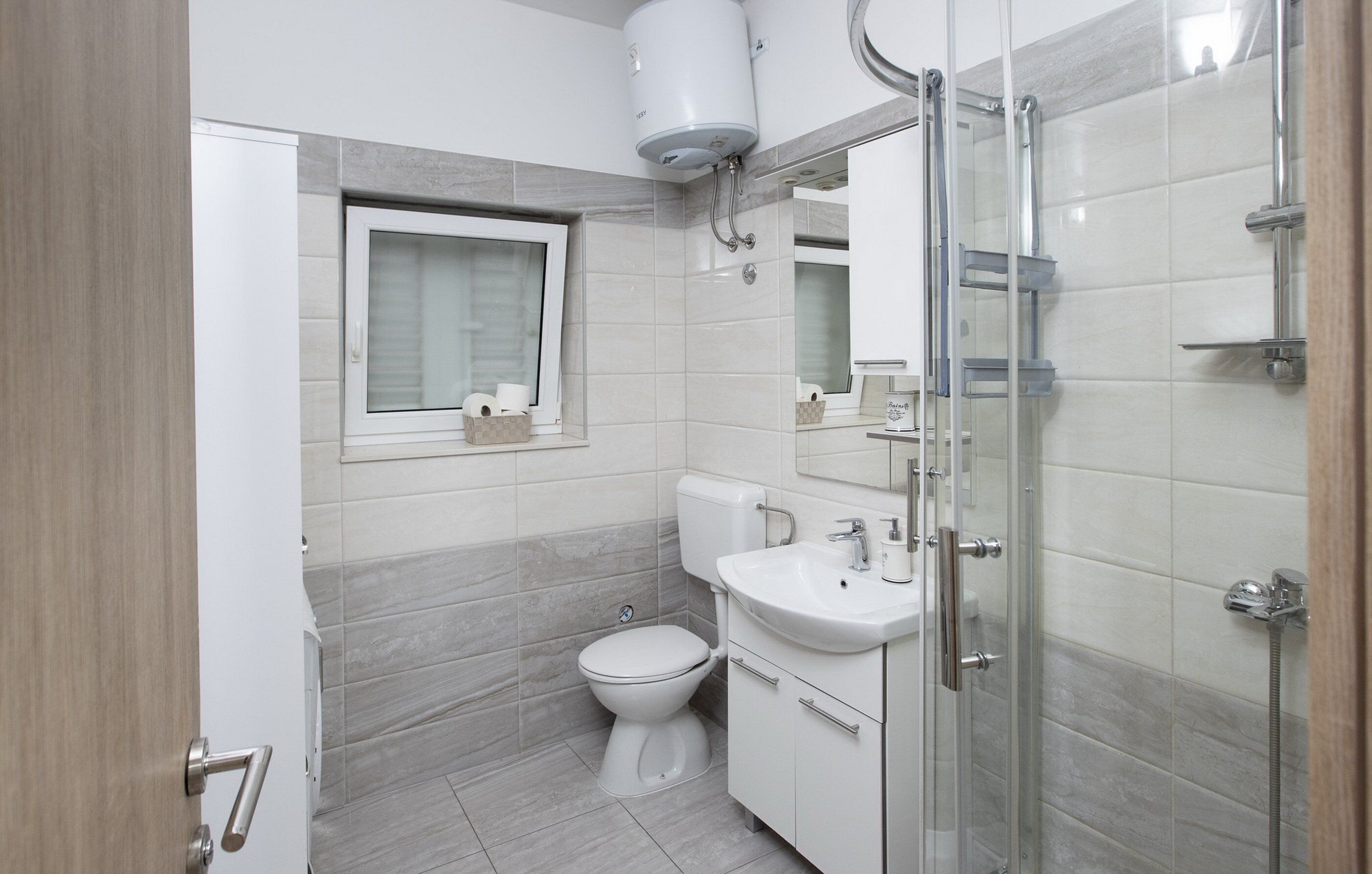A modern bathroom with a toilet, sink, and shower.
