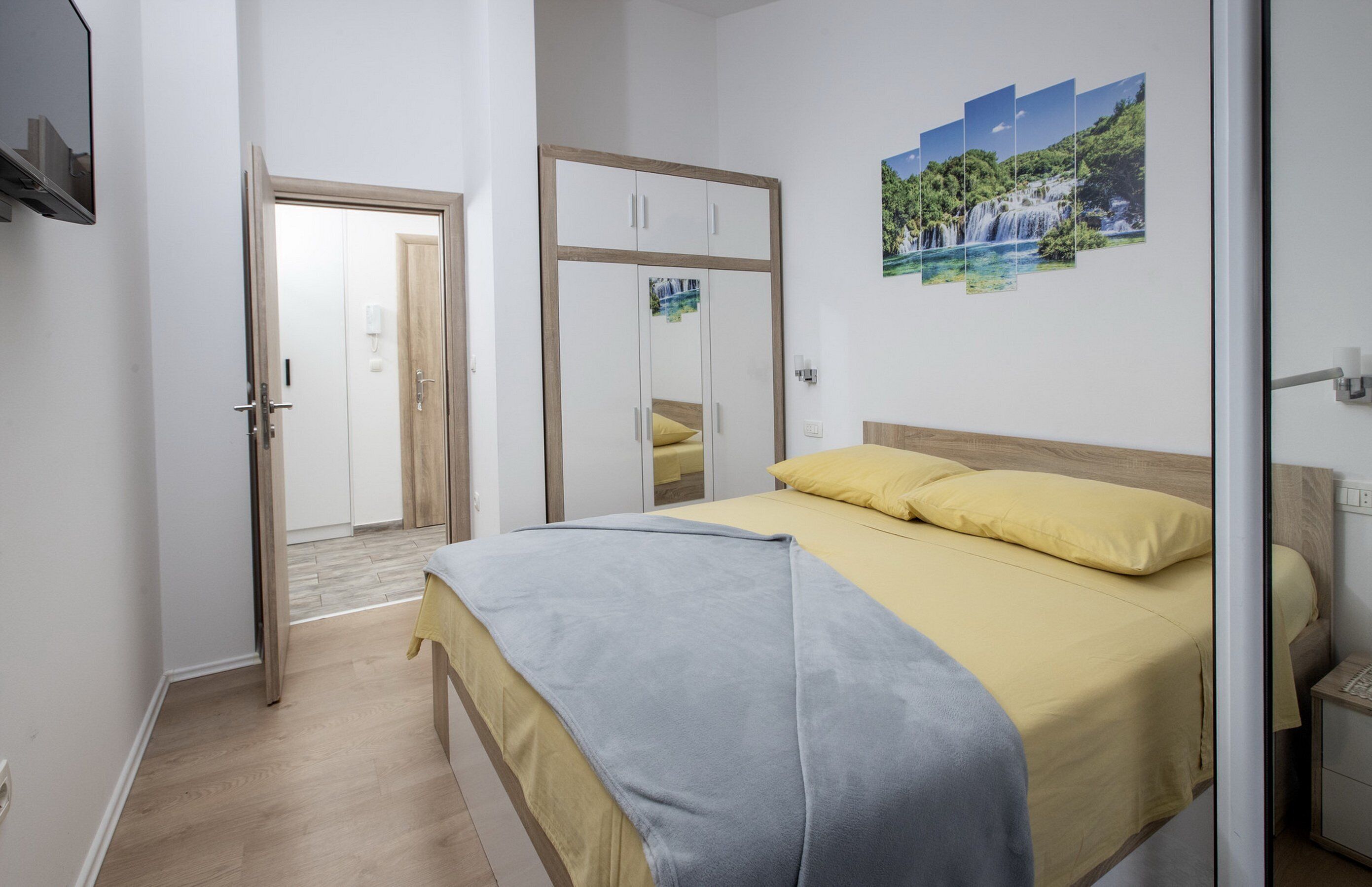Quarto com cama, guarda-roupa e porta que dá para outro cômodo.