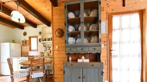 A rustic kitchen with wooden cabinets, a dining table, and a refrigerator. - Tetina Kuća (Saborsko)
