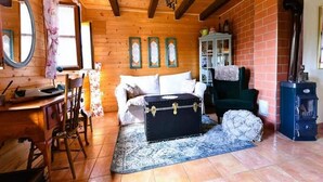 A cozy cabin interior with wooden walls, a fireplace, a bed, a desk, and a chair. - Tetina Kuća (Saborsko)