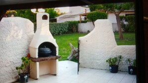 An outdoor patio with a pizza oven, potted plants, and a tiled floor. - Vacations in Corsica (Santa-Maria-Poggio)