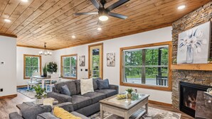 A spacious living room with a fireplace, large windows, and a ceiling fan. - Luxury Cabin|Indoor Pool|Hot Tub|Ping Pong (Sevierville)