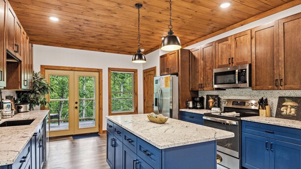 A spacious kitchen with wooden cabinets, granite countertops, stainless steel appliances, and a large island. - Luxury Cabin|Indoor Pool|Hot Tub|Ping Pong (Sevierville)