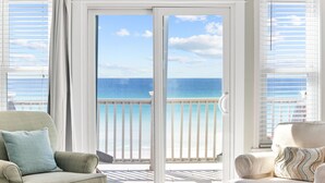Una habitación con vistas al océano a través de amplias puertas corredizas de vidrio.