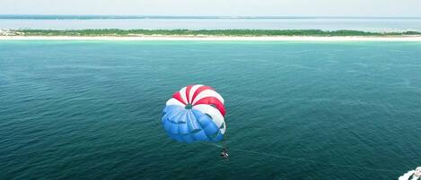Una persona practica parasailing sobre una extensa masa de agua, con una vista despejada de la costa lejana.
