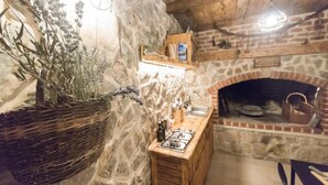 Eine rustikale Küche mit einer Steinwand, einer Holzausstattung und einem Gasherd sowie einem Kamin aus Ziegeln.