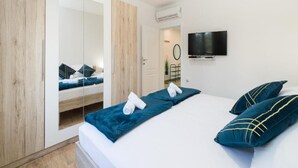 Ein modernes Schlafzimmer mit einem Bett, einem Fernseher und einem Kleiderschrank.