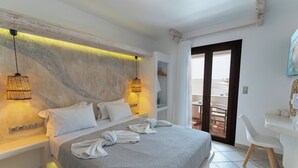 A modern hotel room with a large bed, bedside lamps, a desk, and a balcony. - Nikos Apartments & Studios (Naxos)