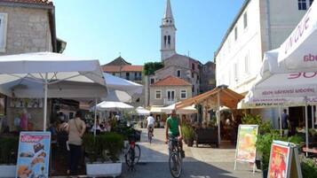 A street with outdoor cafes, a cyclist, and historic buildings.