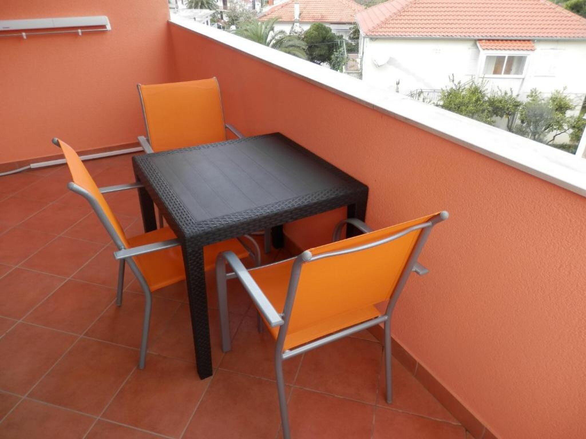 A balcony with a table and four chairs.