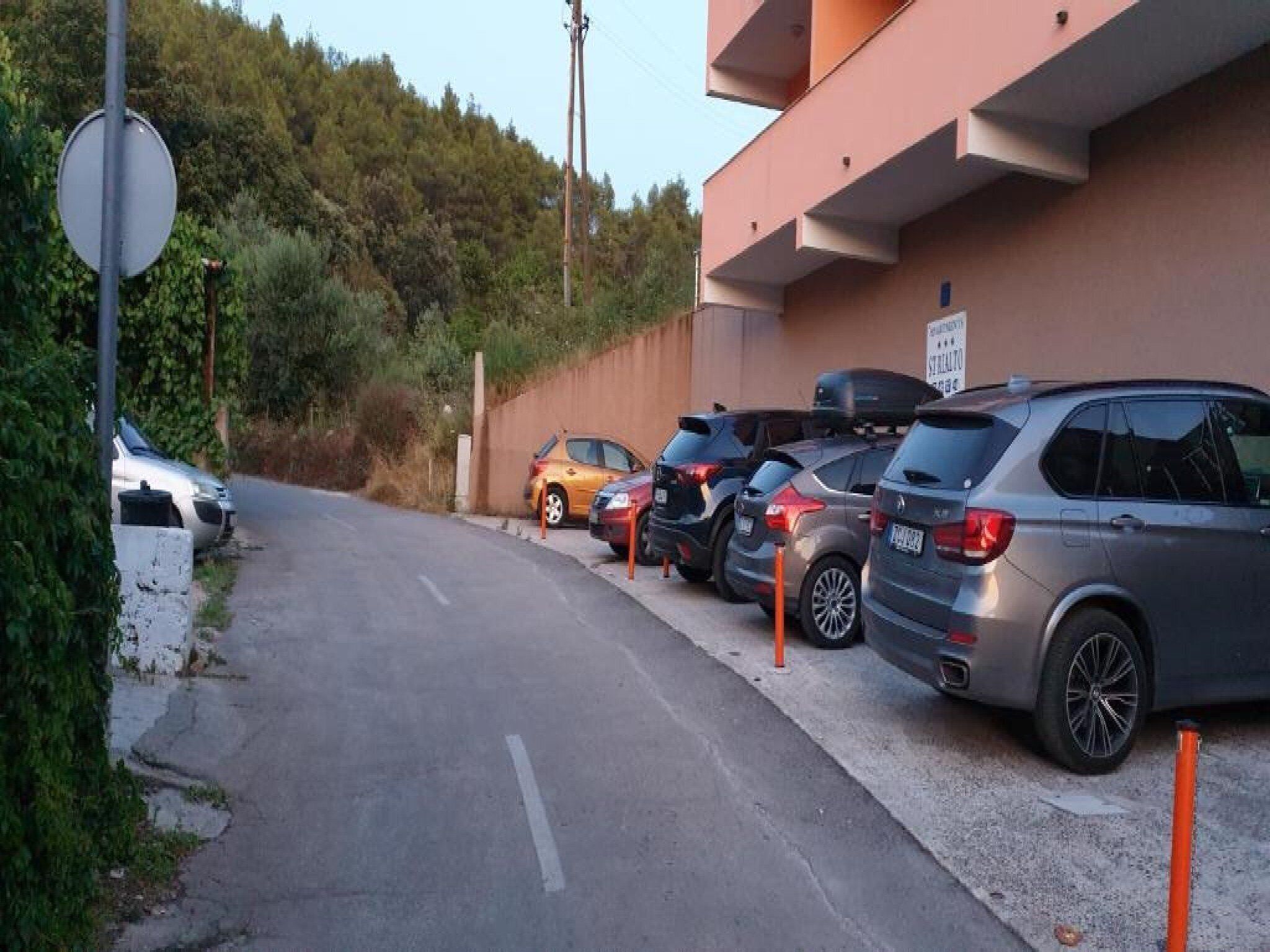 Un espace de stationnement où plusieurs voitures sont garées devant un bâtiment sur lequel est apposée une pancarte indiquant « RÉSERVÉ AU PERSONNEL ».