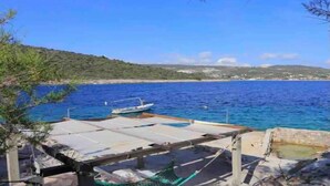 A coastal view with a dock, a hammock, and a boat. - Seafront House Antonia (Rogoznica)