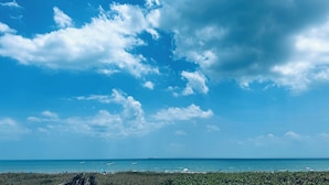 A beach with a clear sky, calm sea, and distant horizon.