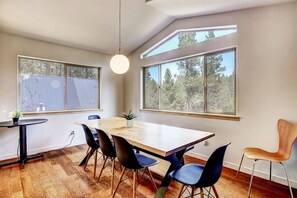 Un comedor moderno con una gran mesa de madera, sillas negras y una lámpara colgante.