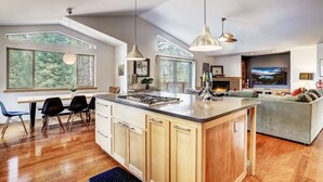 Una cocina amplia con una isla grande, comedor con sillas y sala de estar con sofá.