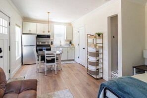 A modern kitchen with white cabinets, a stainless steel refrigerator, and a dining area with a table and chairs.