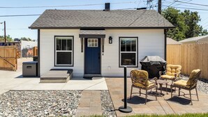 A single-story house with a front door, two windows, a small porch, and outdoor seating with a grill. - Private Urban Cottage in Denver’s RiNo District (Denver)