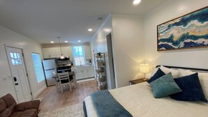 A bedroom with a bed, pillows, a nightstand, a lamp, and a painting on the wall. - Private Urban Cottage in Denver’s RiNo District (Denver)