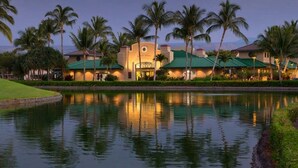 A hotel with a pool, palm trees, and a view of the mountains.