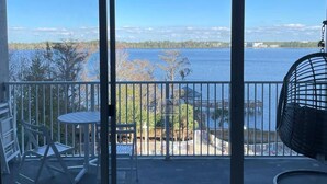 A balcony with a view of a lake, a fan, and outdoor furniture.