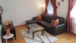 Un salon moderne avec un canapé en cuir, une table basse en verre et une petite table d’appoint.