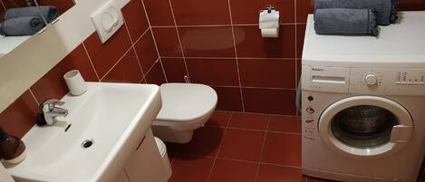 Un baño con lavamanos, inodoro y lavadora.