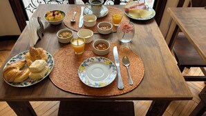 Een ontbijttafel gedekt met croissants, fruit, sap en diverse ontbijtartikelen.