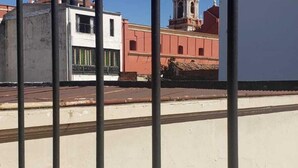 A view through a metal fence with buildings in the background, including a church with a bell tower. - Posta del Ángel (Salta)