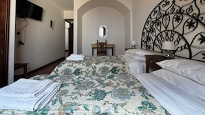 Een hotelkamer met een bed, een bureau, een stoel, een aan de muur bevestigde televisie en een decoratief metalen hoofdeinde.